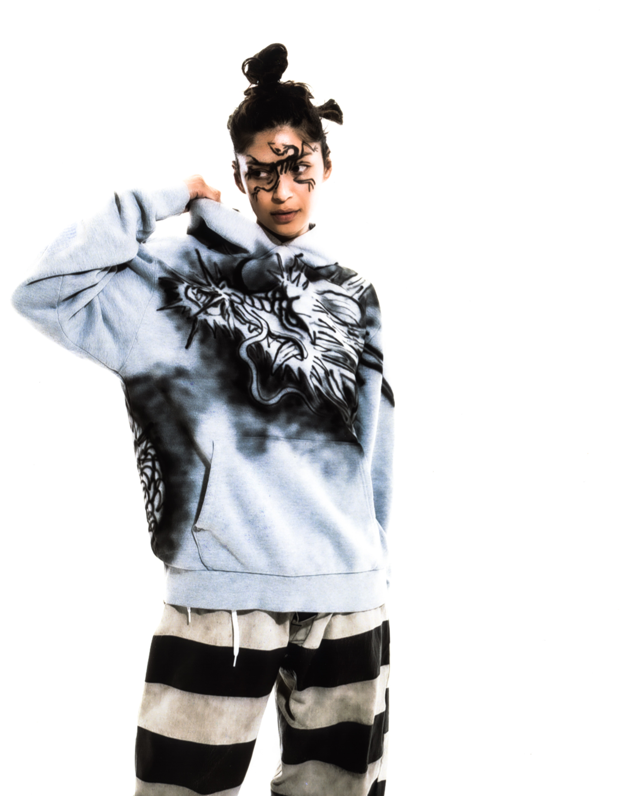 Model wearing black graphic liner and a gray hood with a dragon graphic on it against a white background